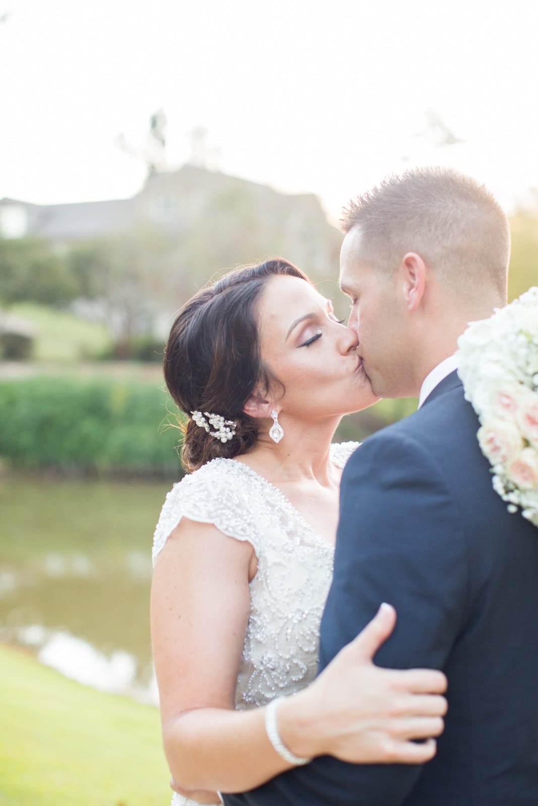 brunette bride kisses her groom in bright and airy outdoor space