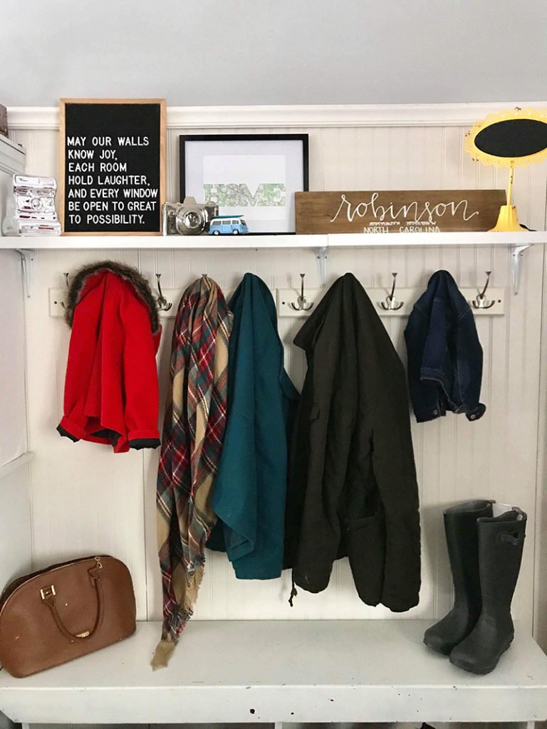 Map print in a drop zone surrounded by other family mementos, coats and entryway signage