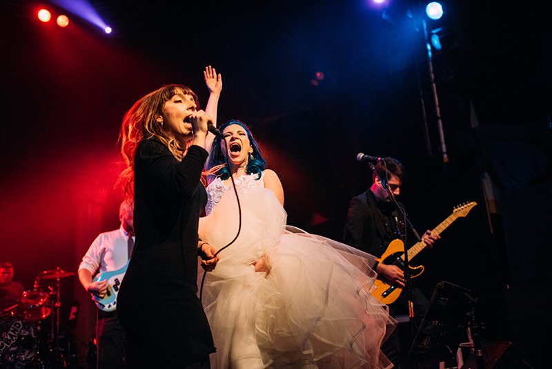 two brides pose nose to nose for wedding portrait holding bouquets