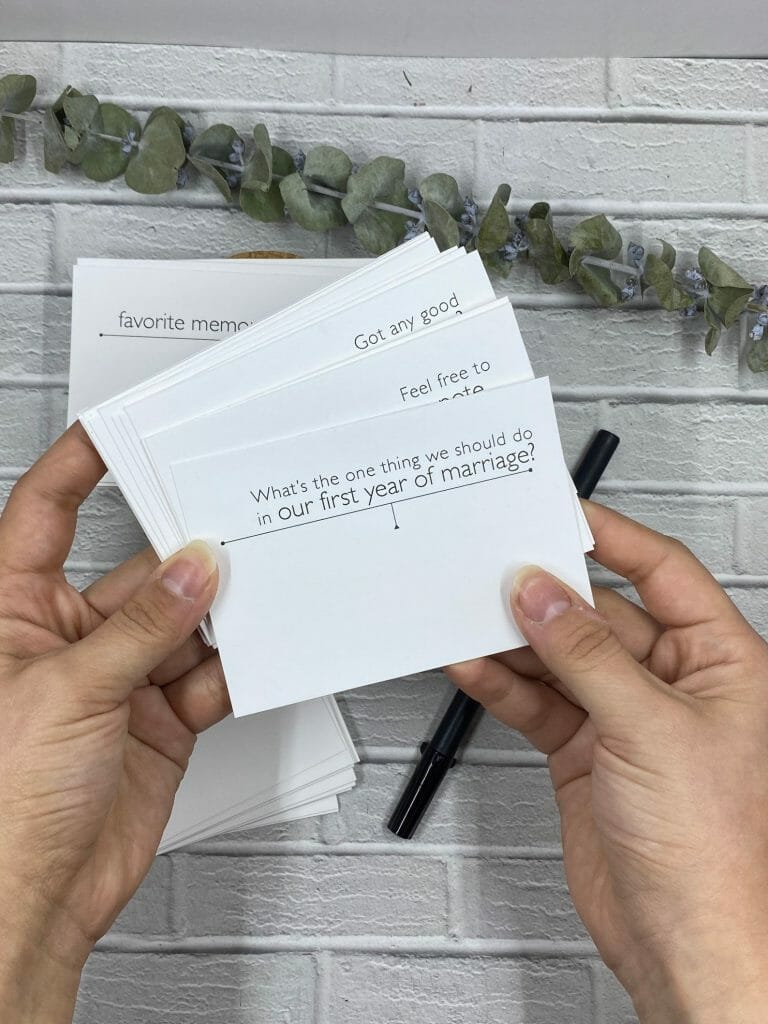 female hands fan out conversation cards for wedding guest messages in photo guestbook